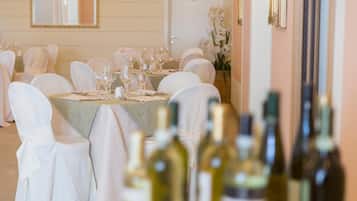 A banquet hall with round tables set for a formal event, each with white tablecloths and glassware.