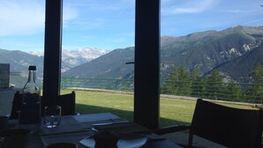Mesa con botella y vaso, con vista a un paisaje montañoso.