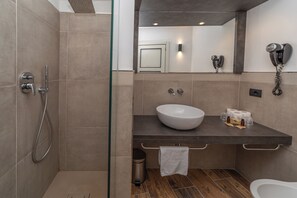 A modern bathroom with a glass shower enclosure, a vessel sink, and a hairdryer mounted on the wall. - Hotel La Torre (Sauze d'Oulx)