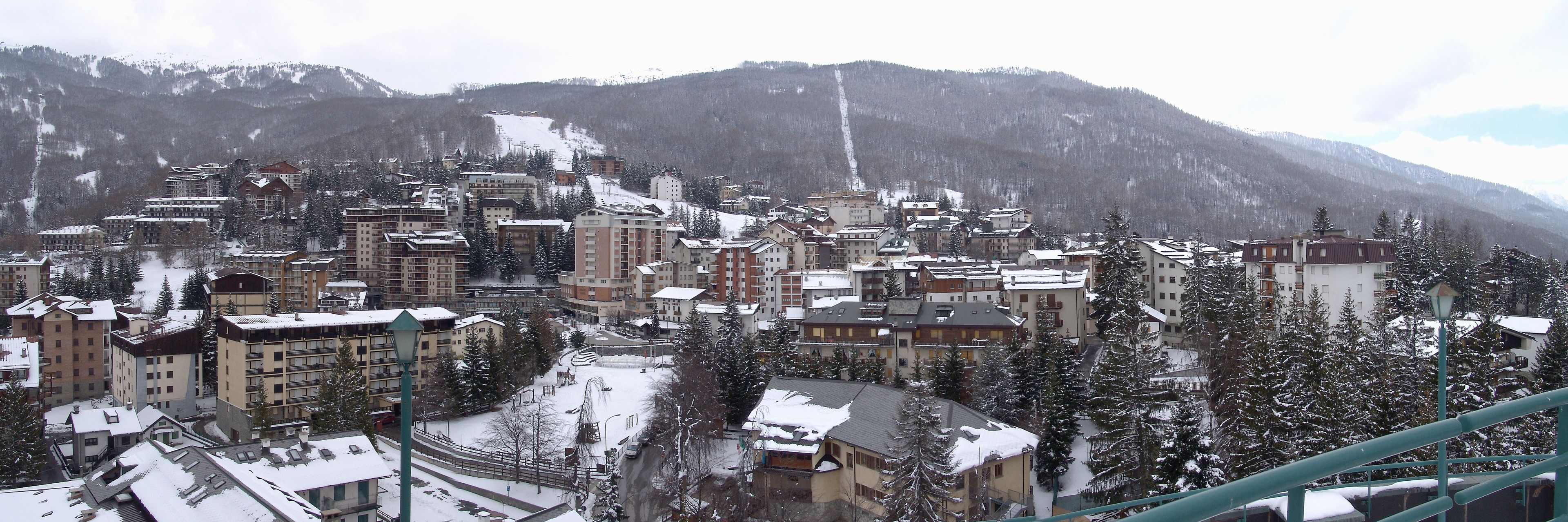 Un pueblo cubierto de nieve, con edificios y montañas al fondo.