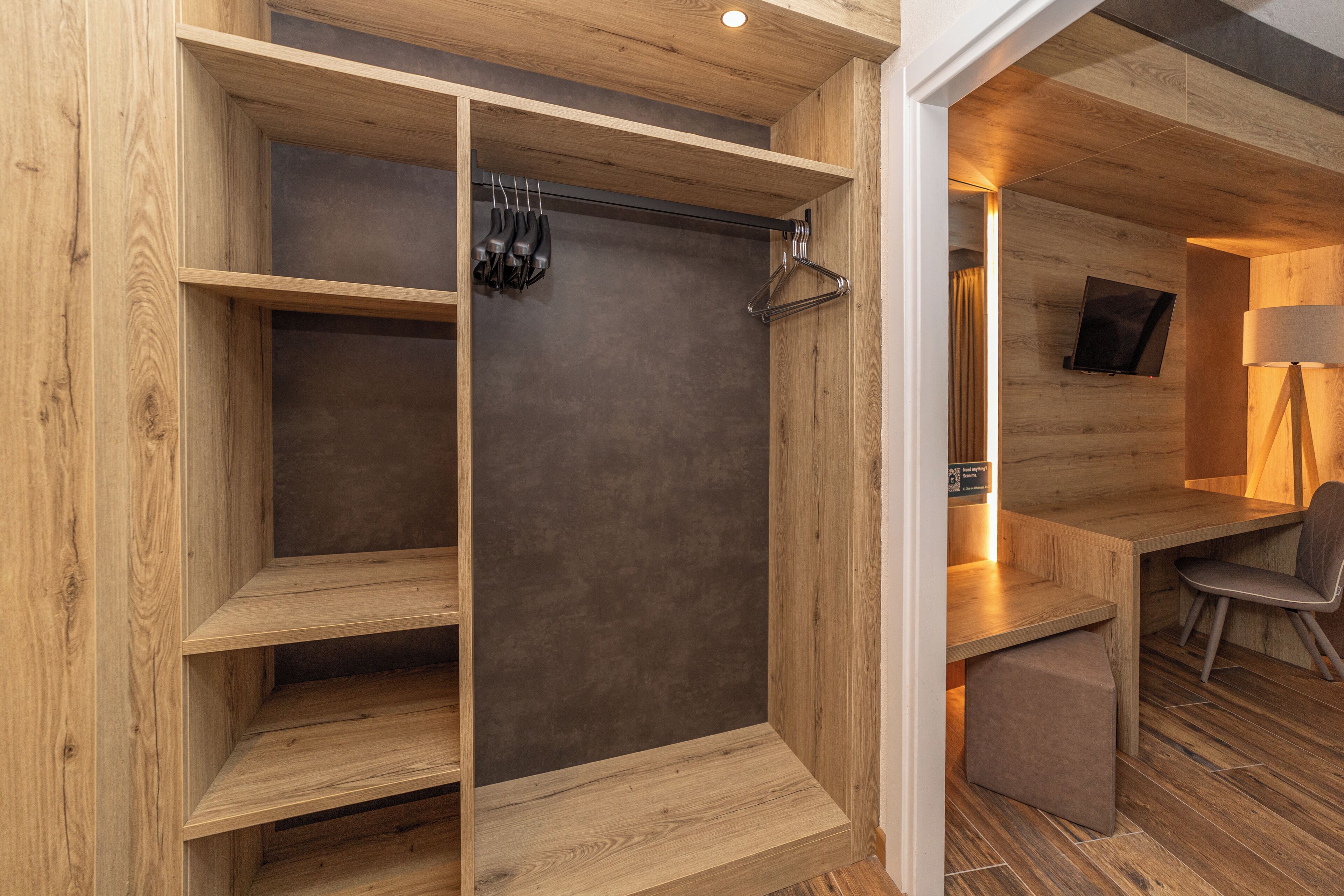A wooden interior with a shower area, a seating area, and a television mounted on the wall.
