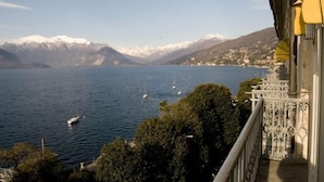 Un balcon offrant une vue sur un lac, des bateaux et des montagnes enneigées.