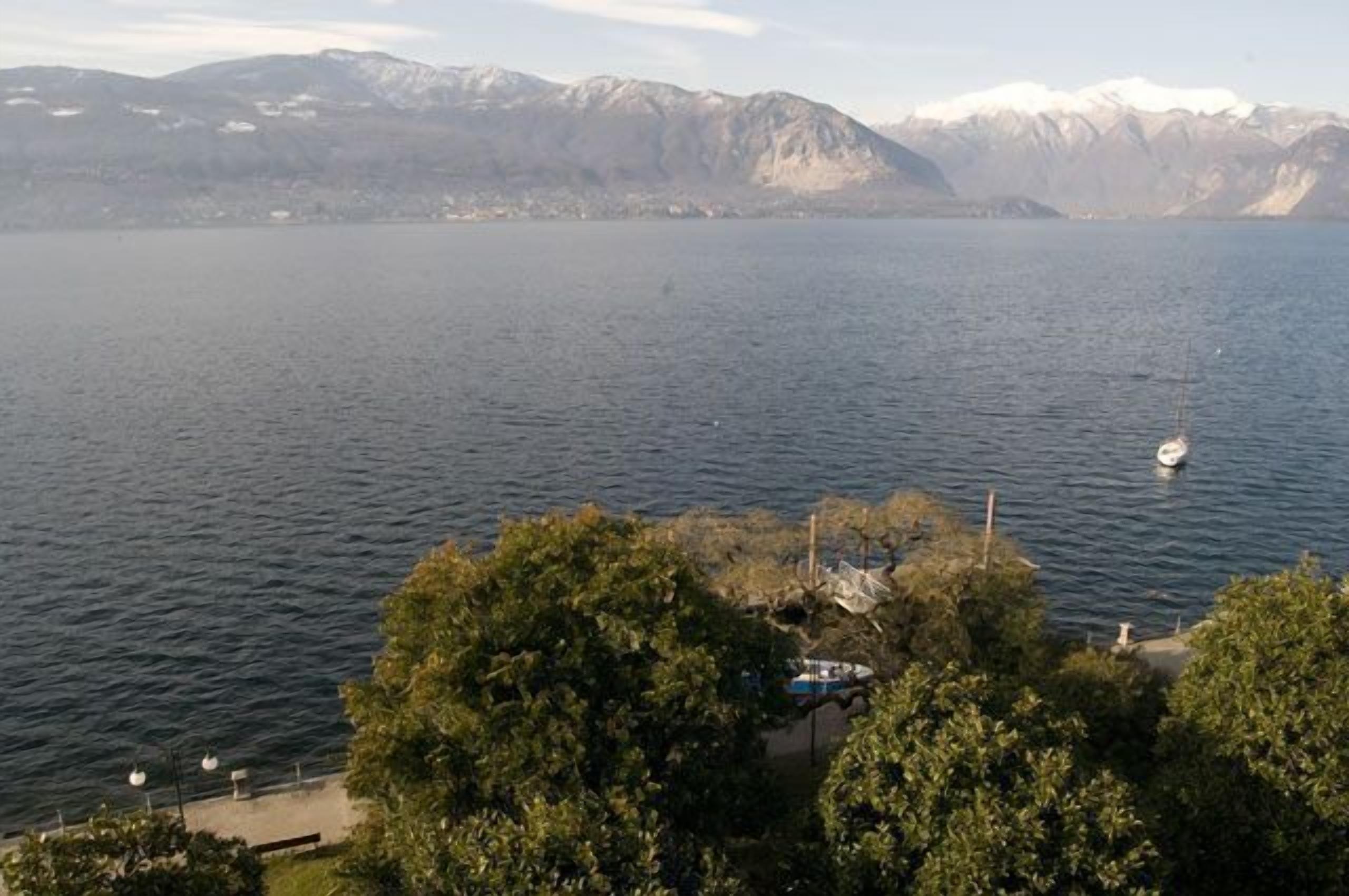 A lake with a boat docked on the shore, surrounded by trees and mountains in the background.