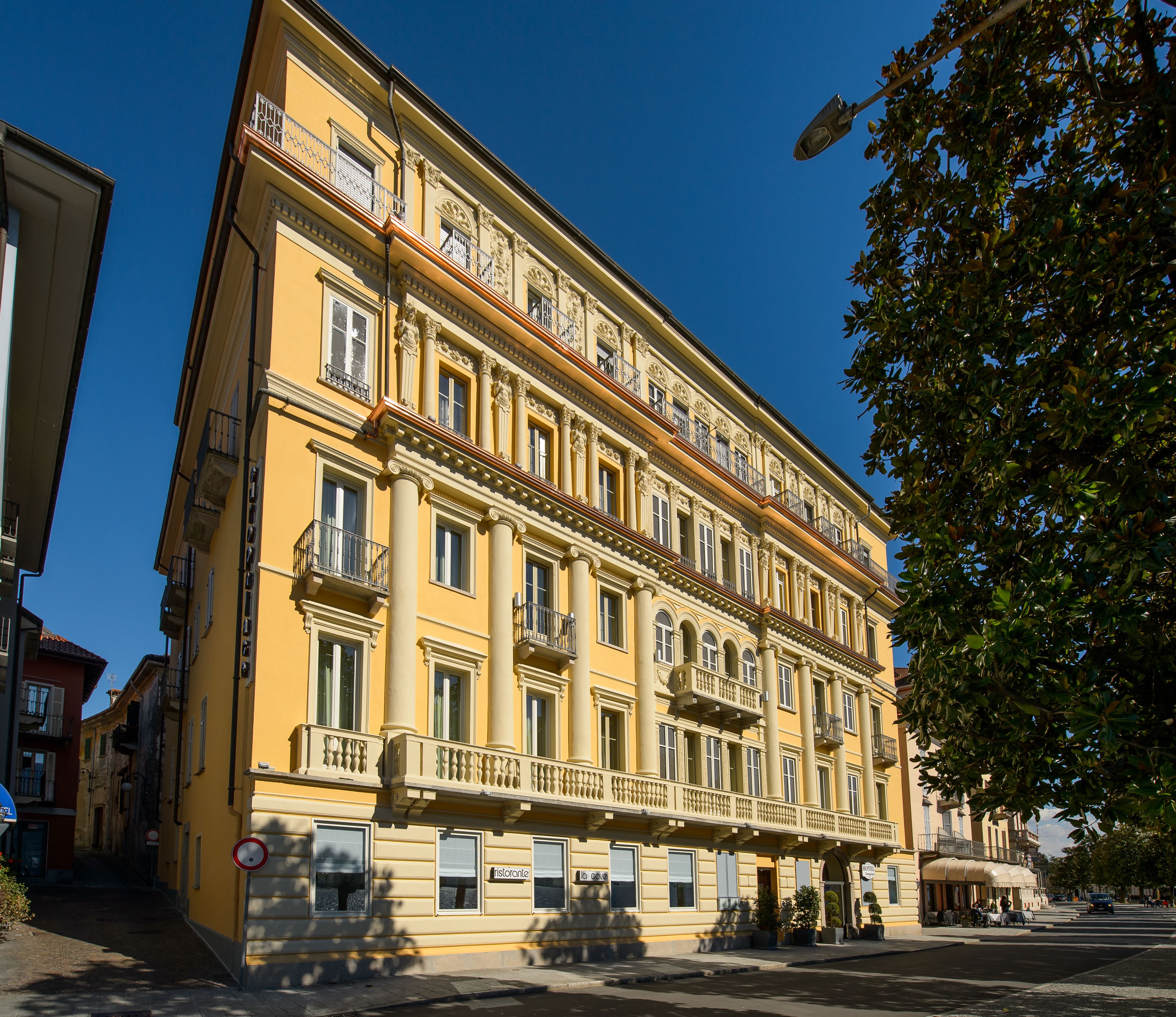 A multi-story yellow building with balconies, large windows, and a street view.