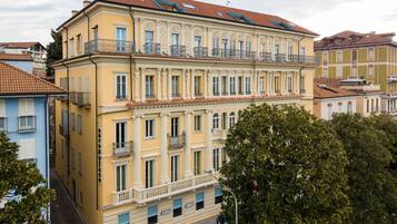 Ein mehrstöckiges Gebäude mit einer gelben Fassade, mehreren Balkonen und einem roten Ziegeldach.