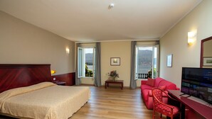 Une chambre d’hôtel avec un lit, un bureau, un canapé rouge et un téléviseur.