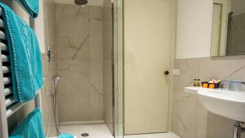 Ein modernes Badezimmer mit einer Duschkabine aus Glas, einem weißen Waschbecken und einer Wand mit Marmorfliesen.