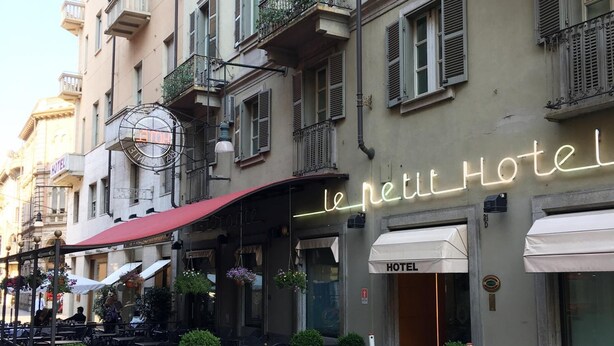 A hotel with outdoor seating and a neon sign. - Le Petit Hotel (Turin)