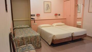 A bedroom with two beds, a bench, a wardrobe, and a bedside table.