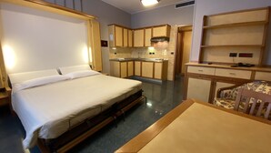 A compact hotel room with a single bed, a small kitchenette, and a desk with a chair. - Le Petit Hotel (Turin)