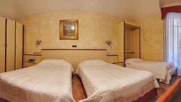 Camera d'albergo con due letti, un quadro appeso al muro e uno specchio.