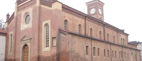 A large brick building with a clock tower and a central arched doorway.