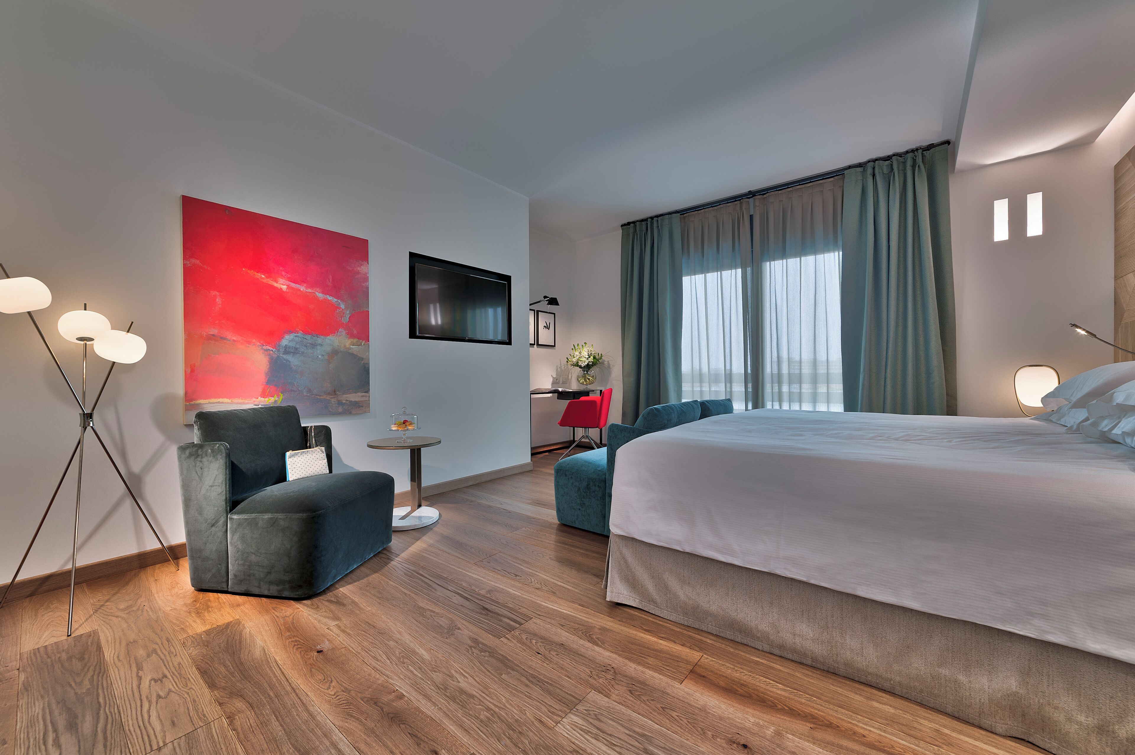 Quarto de hotel moderno com uma cama grande, uma escrivaninha, uma cadeira e um sofá.