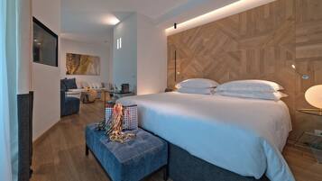 A modern hotel room with a large bed, a seating area with a table, and a wooden accent wall.