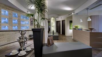 En modern hotellobby med en receptionsdisk, en sittgrupp och ett utställningsområde med hygienartiklar.