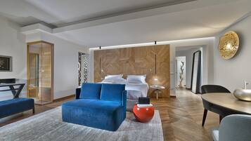 Ein modernes Hotelzimmer mit einem blauen Sofa, einem roten kugelförmigen Tisch und einer Wand mit Holzpaneelen.