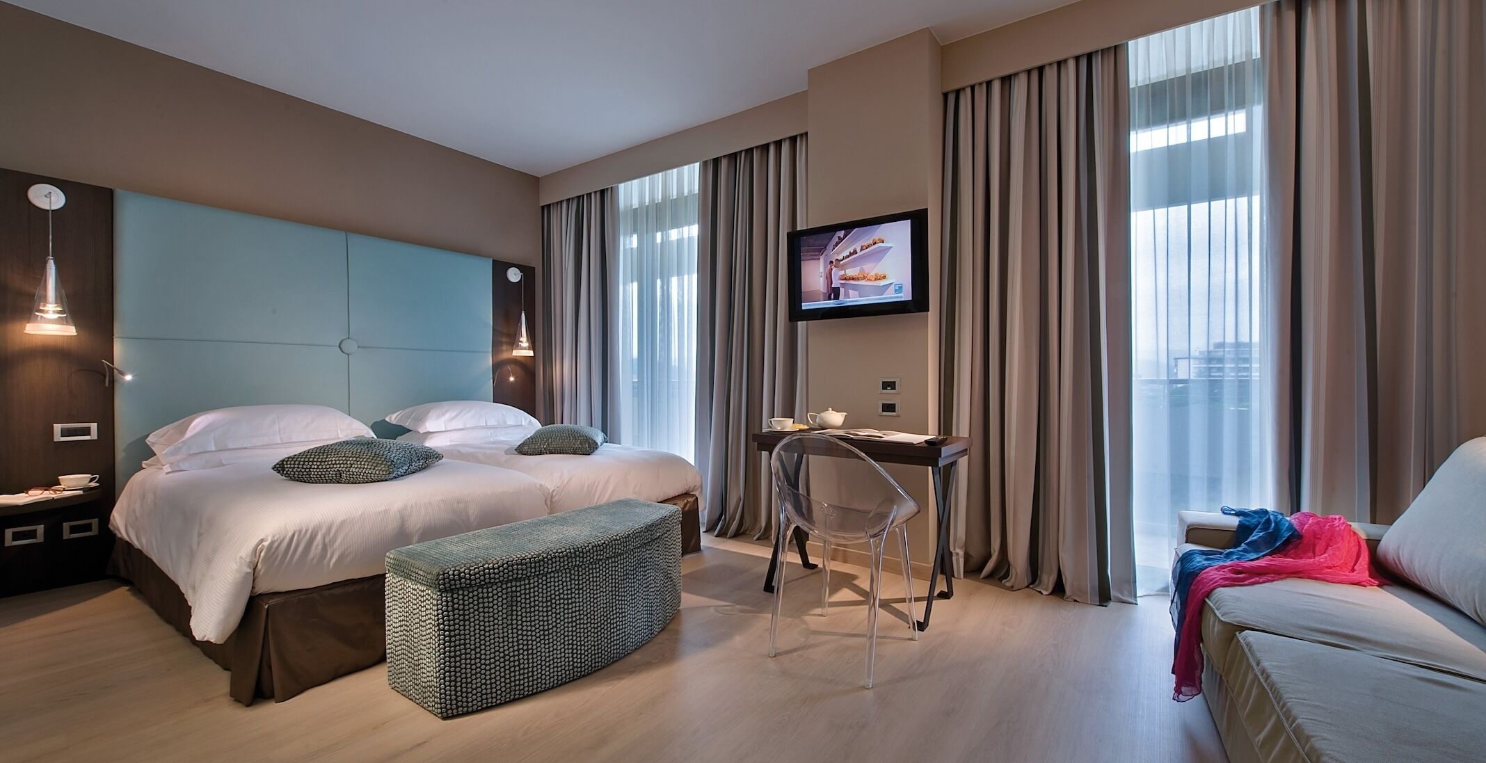 Een hotelkamer met een bed, bureau, stoel en televisie.