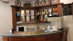 A bar area with a coffee machine, shelves with bottles, and a menu board. - Hotel Italia (Turin)
