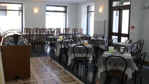 A dining area with multiple tables and chairs, a central decorative structure, and large windows allowing natural light. - Hotel Italia (Turin)
