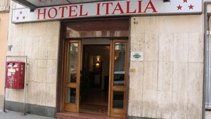 The entrance to Hotel Italia with a sign above the door, a mailbox on the left, and a small sign indicating the hotel's location. - Hotel Italia (Turin)