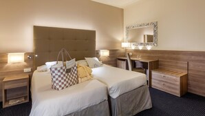 Ein Hotelzimmer mit einem großen Bett, einem Schreibtisch, einem Sessel, einem Schminktisch und einem Spiegel.