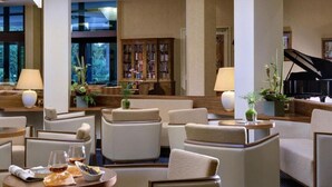 Eine Hotelhalle mit gemütlicher Sitzgelegenheit, einem Klavier und einer großen Bücherwand.