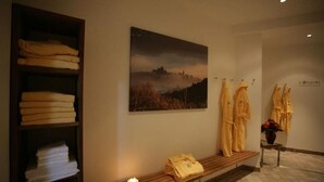 Ein Wellnessbereich mit einer hölzernen Sitzbank, Handtüchern und Bademänteln an Haken.