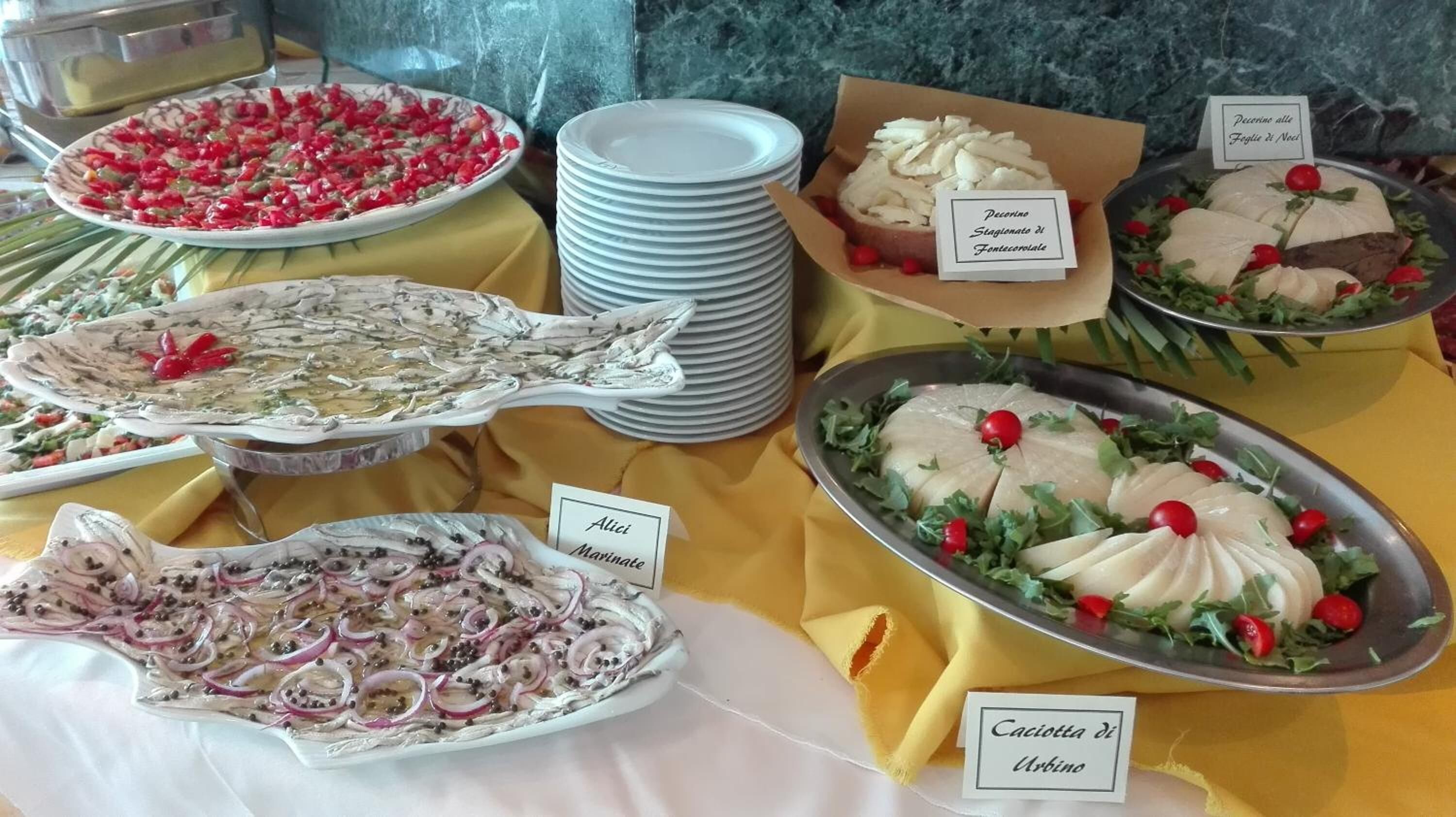 Una mesa de bufé con diversos platos, incluyendo un pescado, una tabla de quesos y una ensalada.