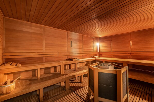A sauna with wooden benches and a central heating unit.