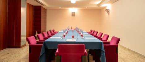 A conference room with a long table, red chairs, and a blue tablecloth.