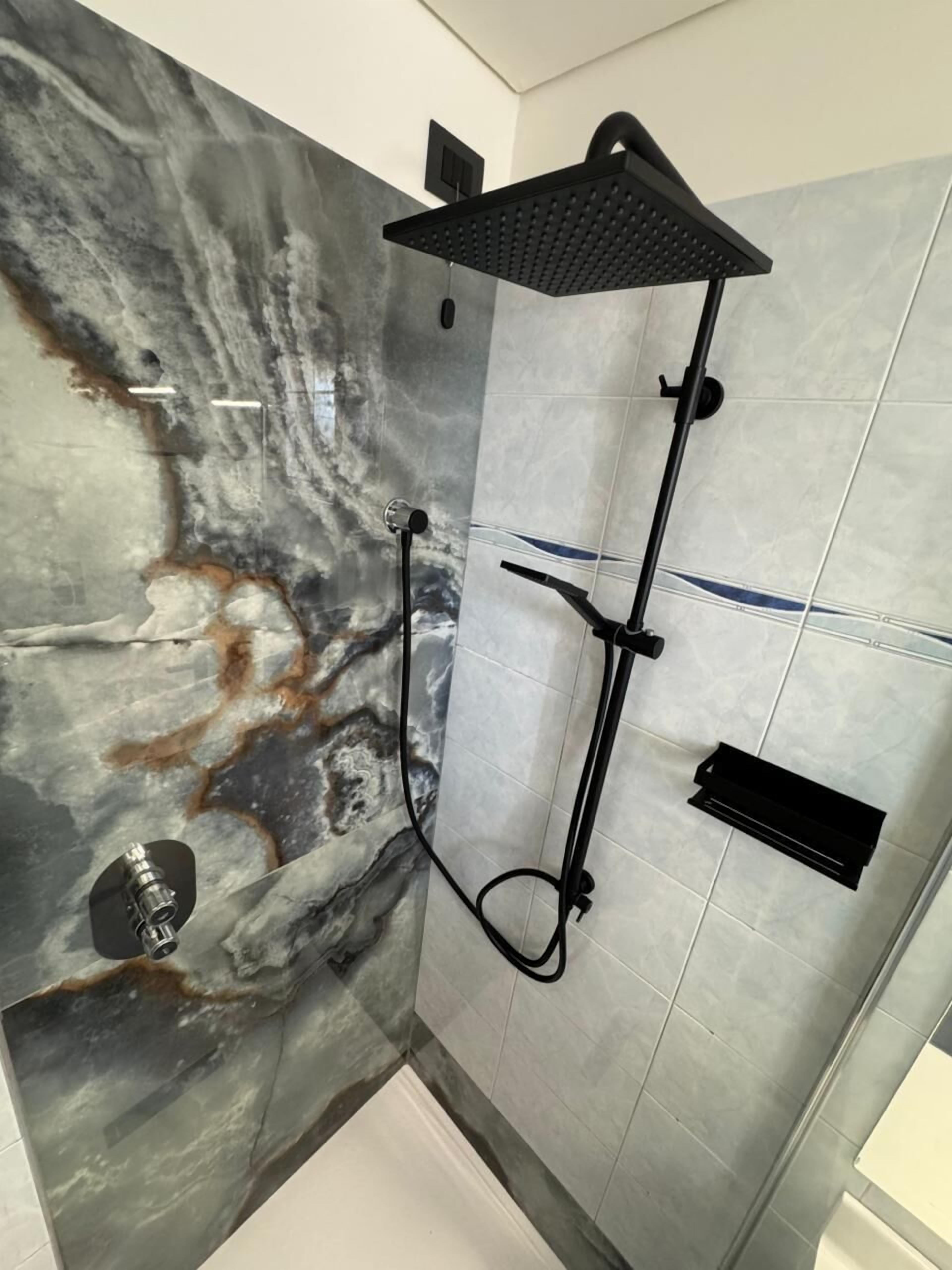 Eine Dusche mit Kopfbrause, Handbrause und einer fest installierten Bedienfeld.