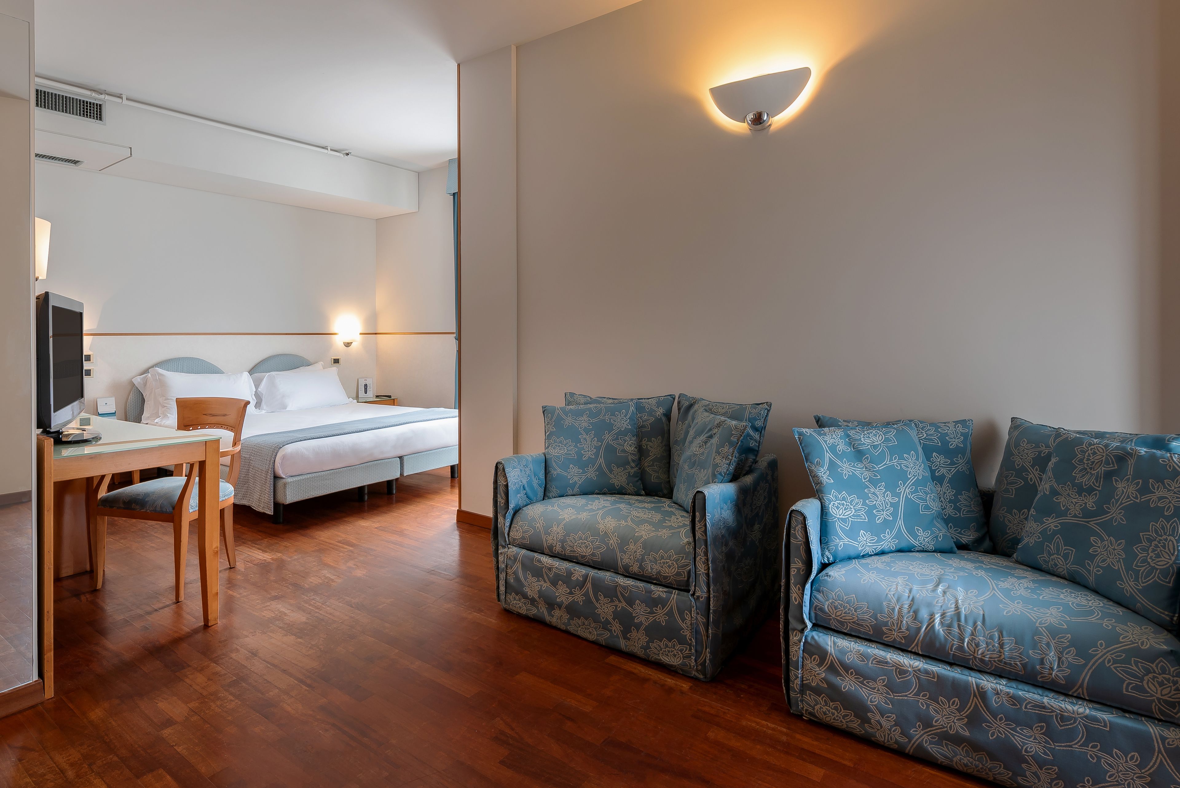 Una habitación de hotel con cama, escritorio y sofá.