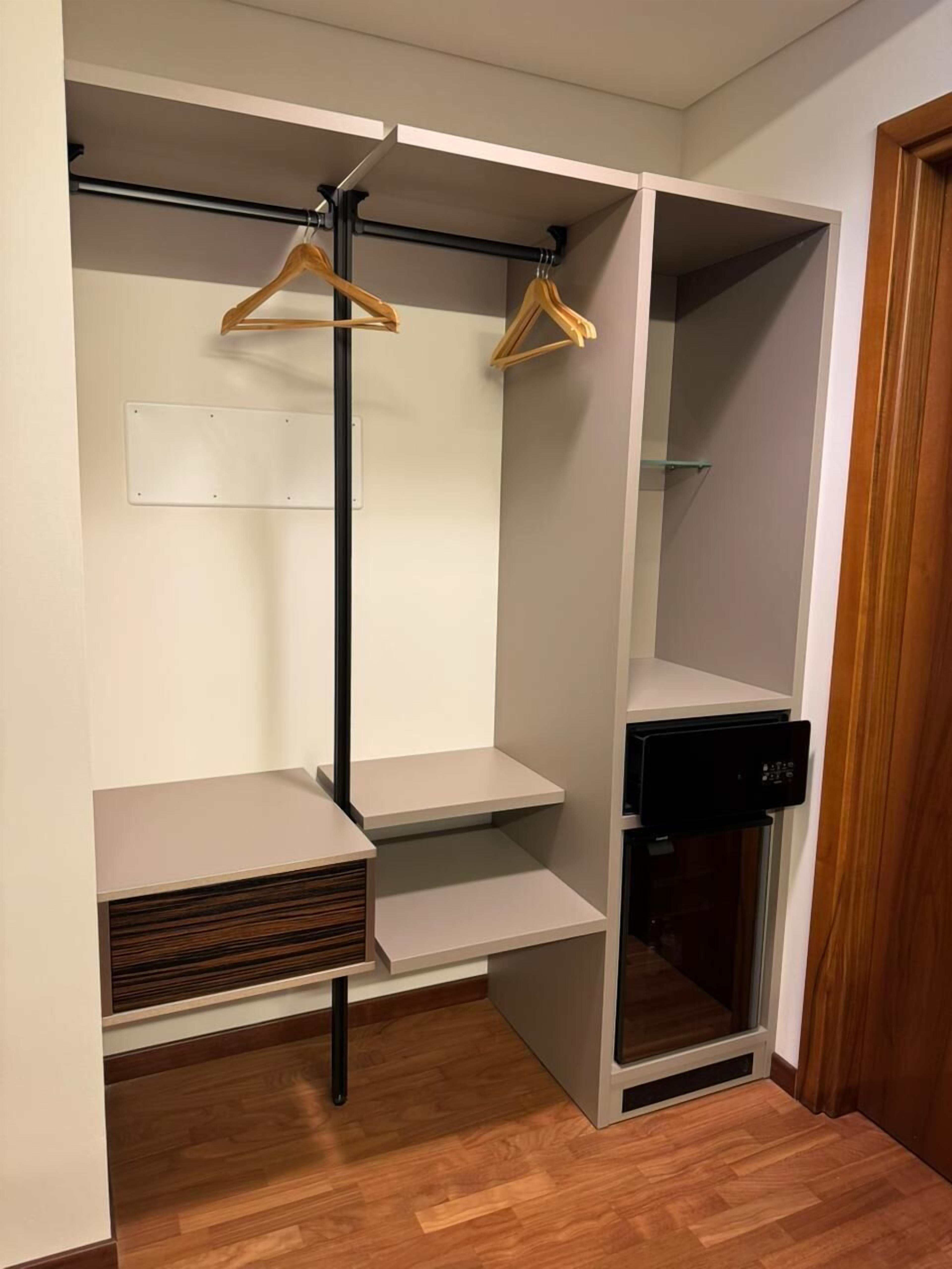 A walk-in closet with wooden hangers, a black appliance, and a wooden cabinet.