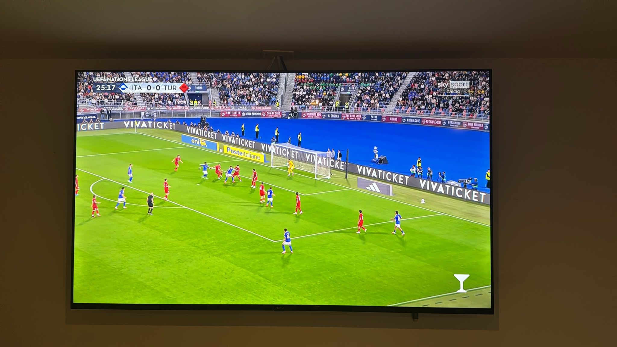 A television screen displaying a soccer match with players in red and blue jerseys.