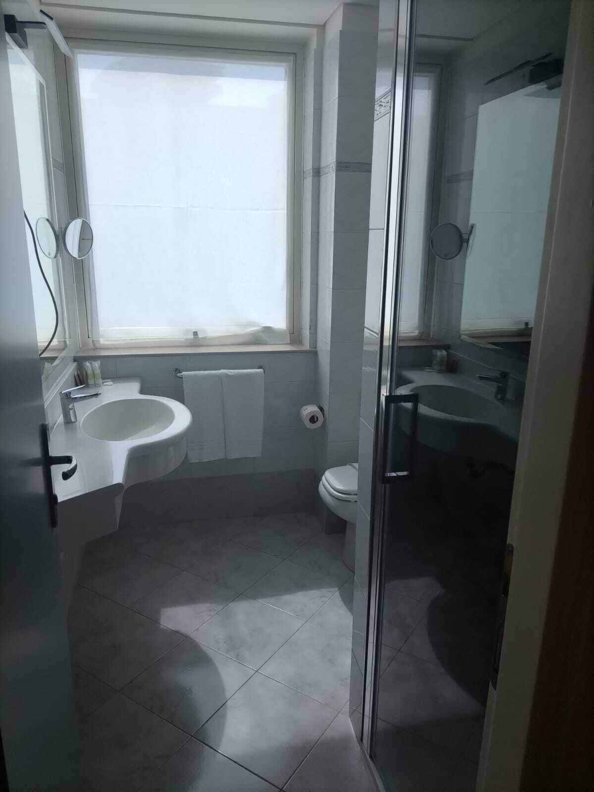 A bathroom with a toilet, sink, and shower area.