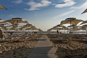 Een strand met rijen zonneschermen en ligstoelen.