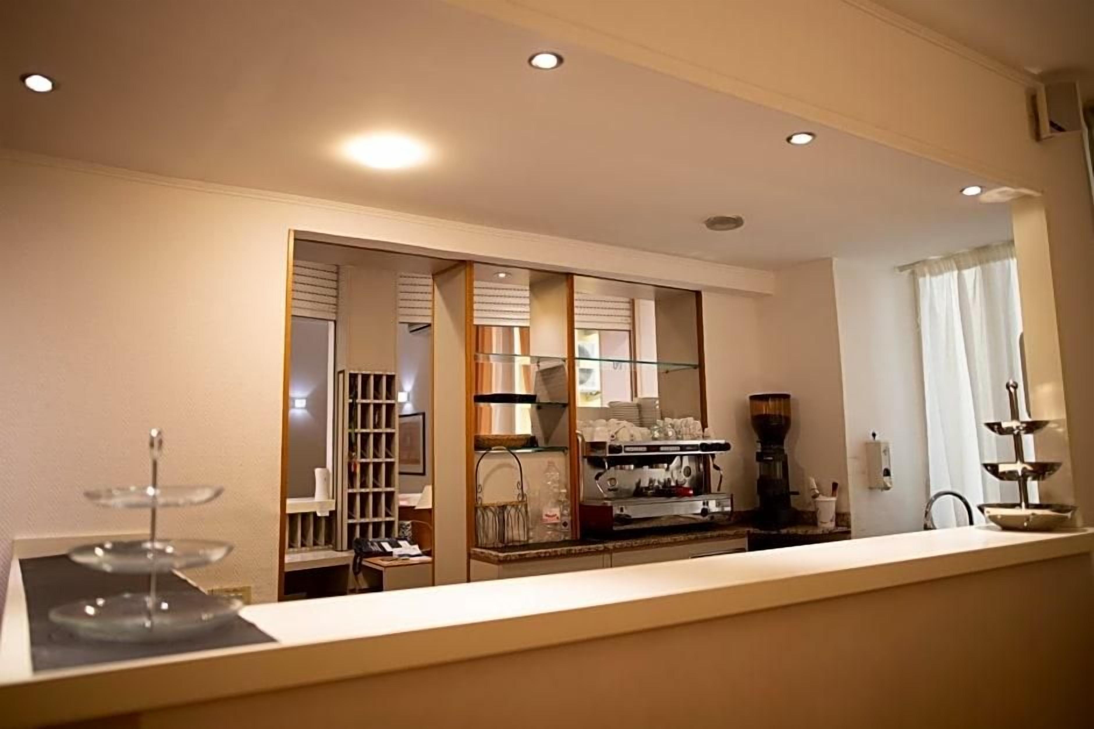 Een hotel receptie met een balie, een koffieapparaat en een glazen vitrine.