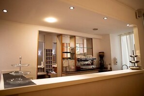 A hotel reception area with a counter, a coffee machine, and a glass display case. - Hotel Arcadia (Macerata)