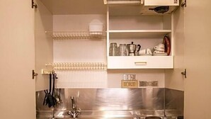A compact kitchen with stainless steel appliances, white cabinetry, and a small countertop area. - Hotel Arcadia (Macerata)