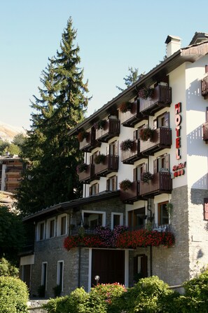 Un hôtel doté de nombreux balcons, d’une façade en pierre et de jardinières fleuries.