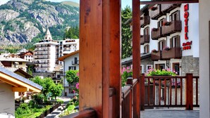 A hotel with balconies, a mountain backdrop, and a stone pathway.