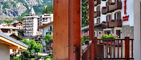 A hotel with balconies, a mountain backdrop, and a stone pathway.