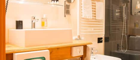 A bathroom with a sink, mirror, towel rack, and a glass-enclosed shower area.