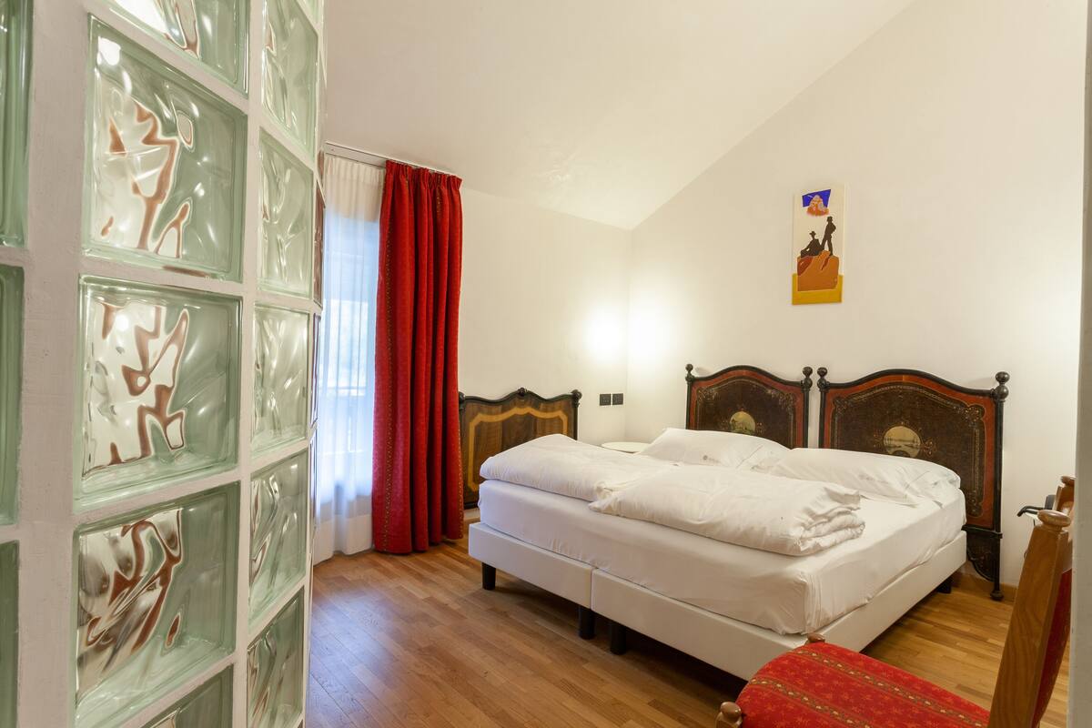 A bedroom with a wooden bed, a glass block wall, and a red curtain.