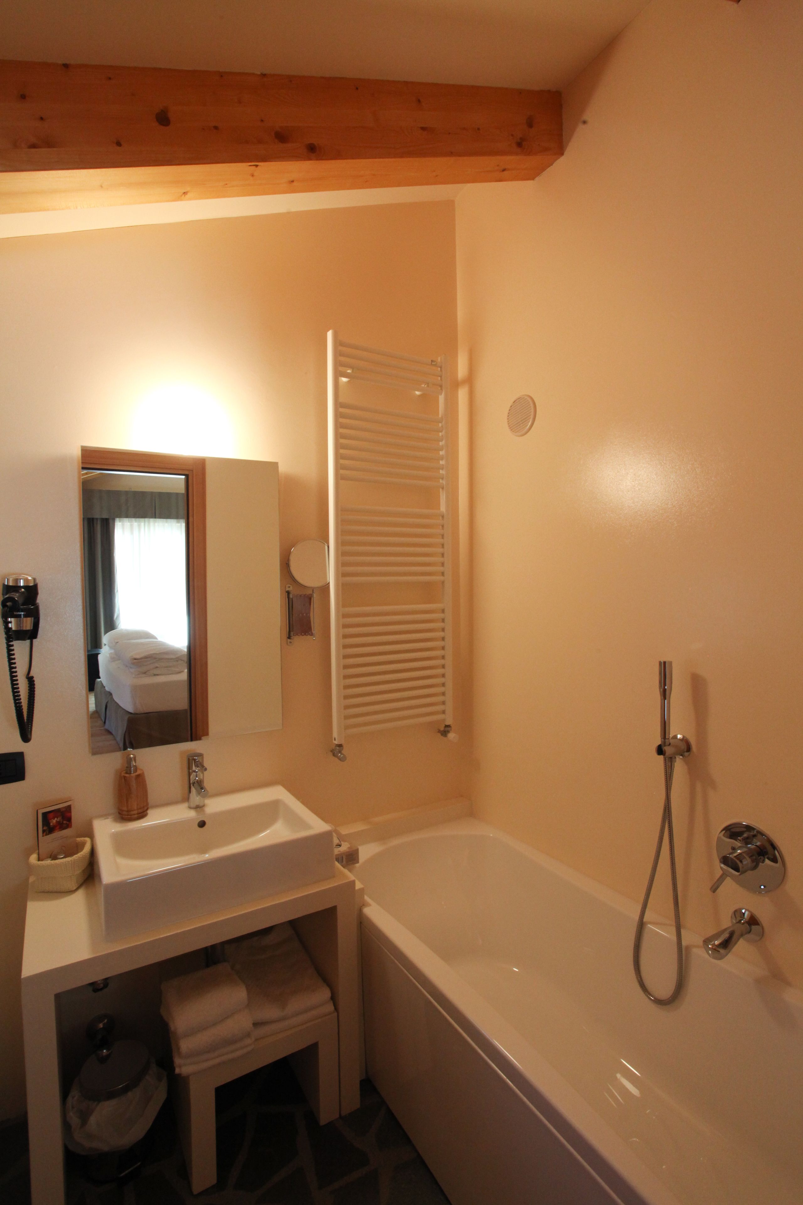 A bathroom with a sink, mirror, towel rack, and a shower.