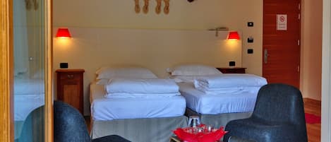 Habitación de hotel con dos camas, una mesita con mantel rojo, dos sillones y cornamentas de ciervo colgadas en la pared.