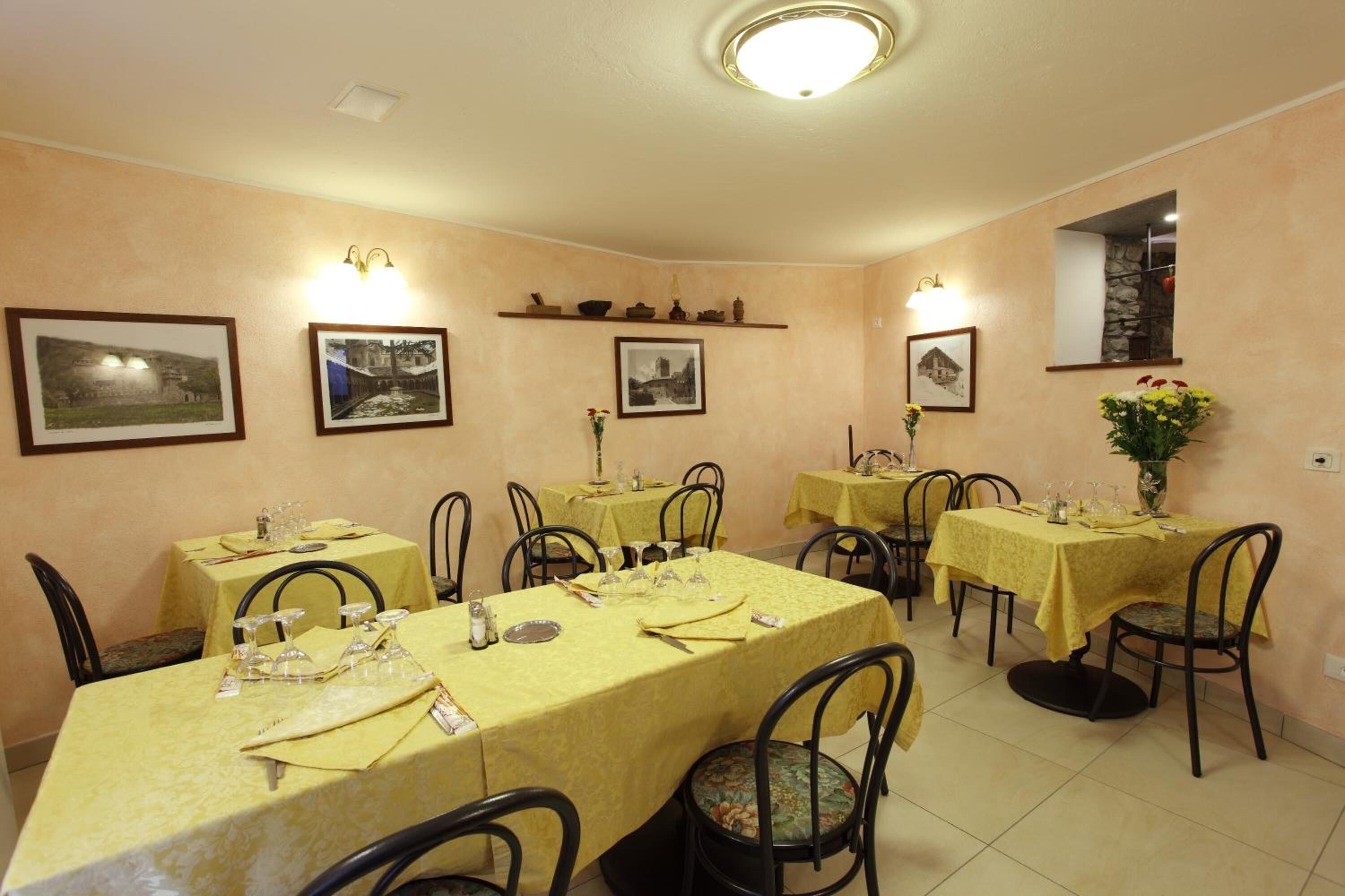 Un comedor con varias mesas dispuestas para recibir a los comensales, cada una con sillas y preparación para servir.