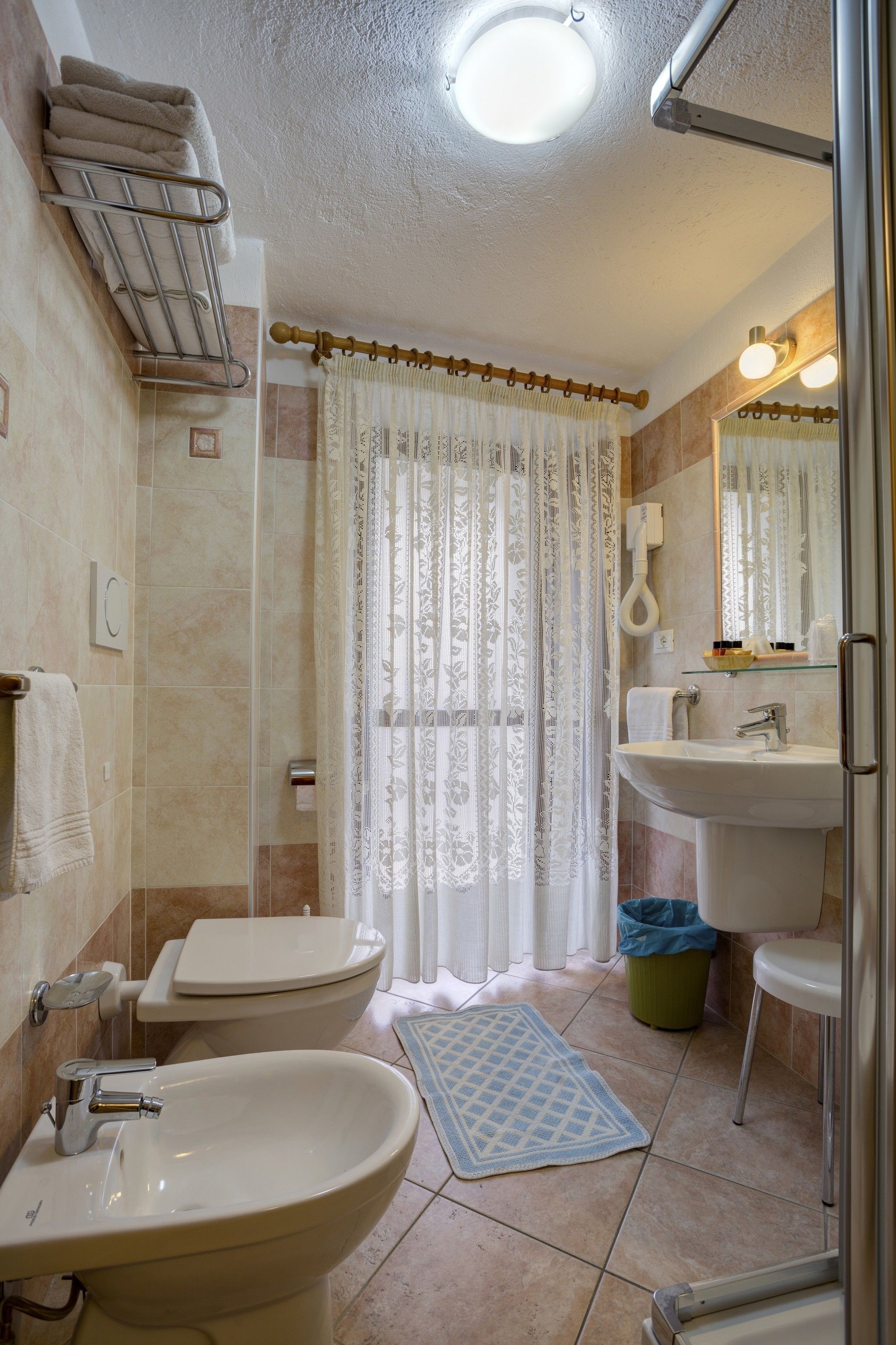 A bathroom with a toilet, bidet, sink, and shower area.