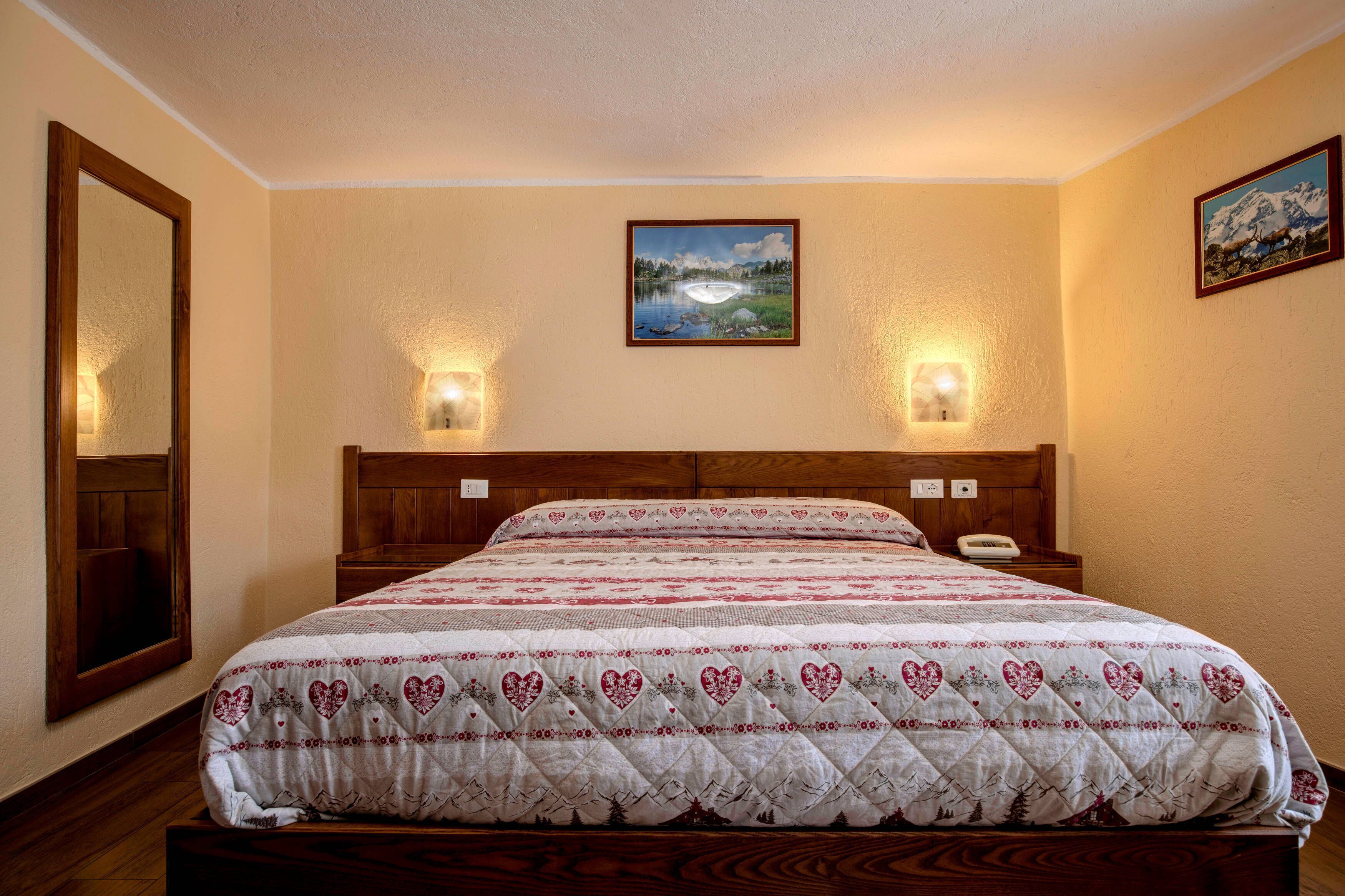 A neatly made bed with a quilted cover, two bedside lamps, and a framed picture on the wall.