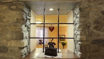 Un rincón de paredes de piedra con un banco de madera, una máquina de escribir antigua y un adorno con forma de corazón colgante.